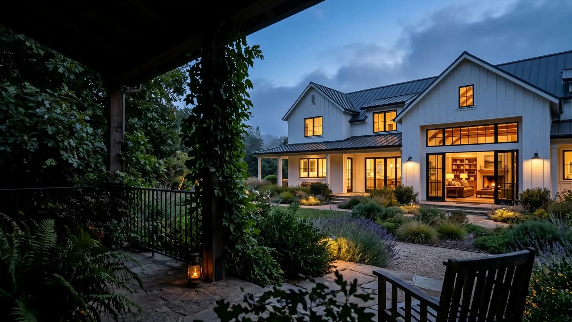 Farmhouse with a lit porch and garden at dusk
